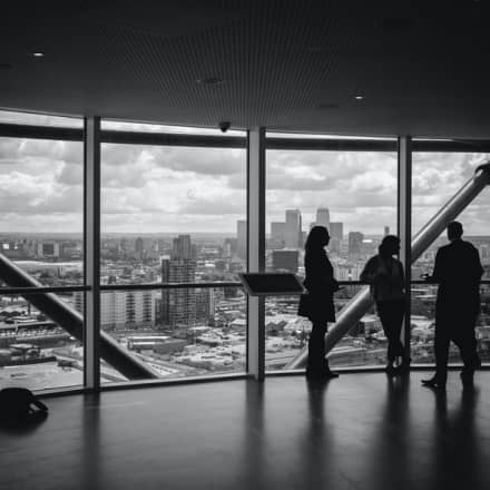 Three people are standing in a room with a view of the city.