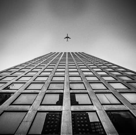 A large building with a plane flying overhead.