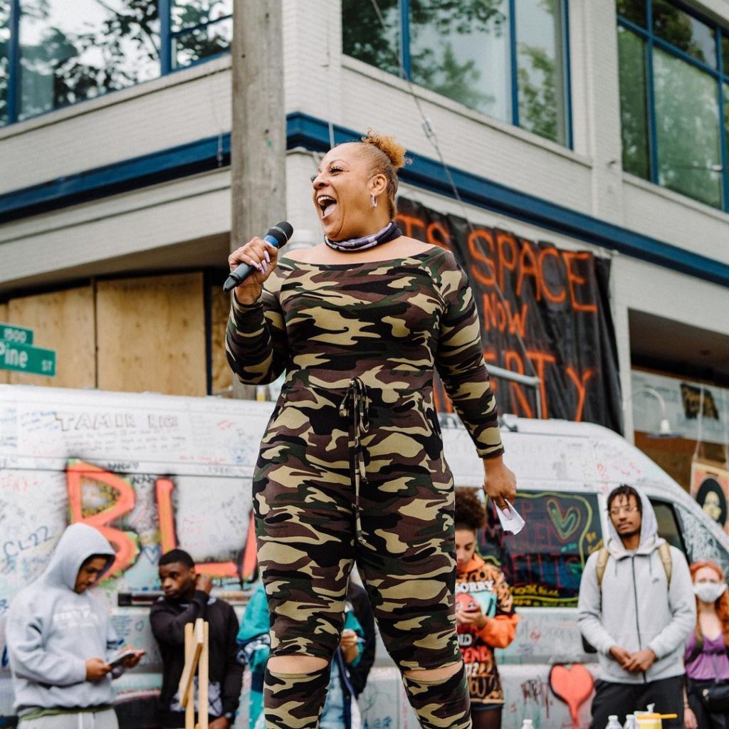 A woman in camouflage clothing is singing.