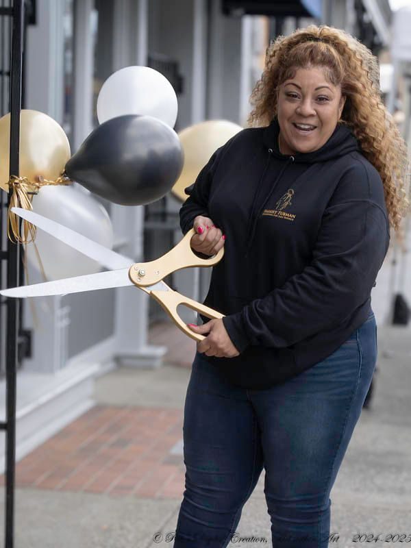 A woman holding scissors cutting the ribbon for a store.