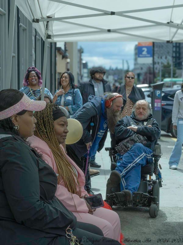 A group of people sitting on the sidewalk.